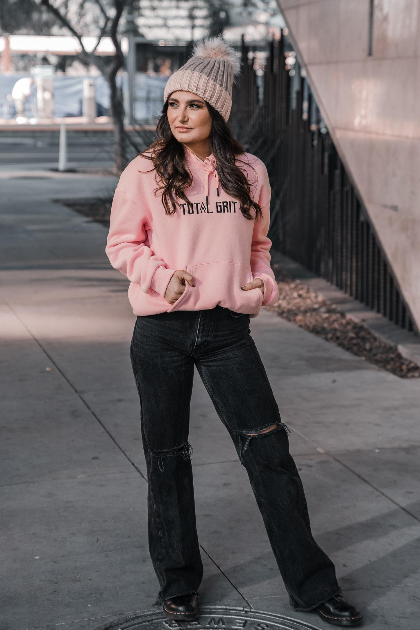 Female model of the light pink Pastel Hoodie, front on. Worn in a casual setting.