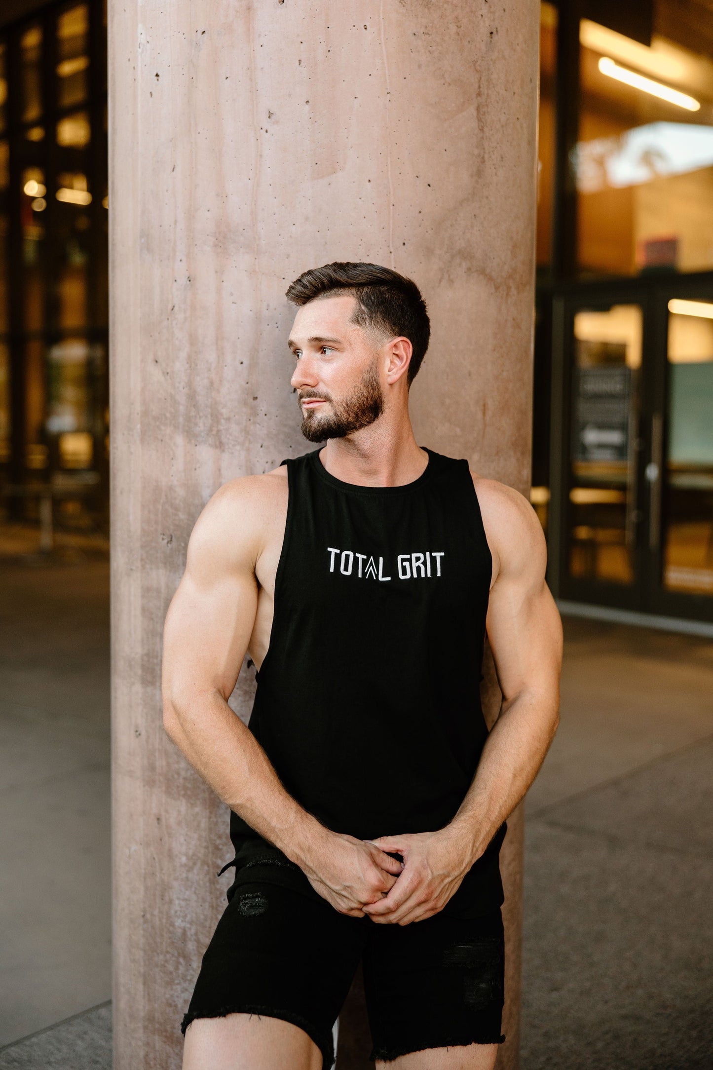 Total Grit cut-off tank shows the white logo on black fabric. The custom embroidered logo is top-tier quality.