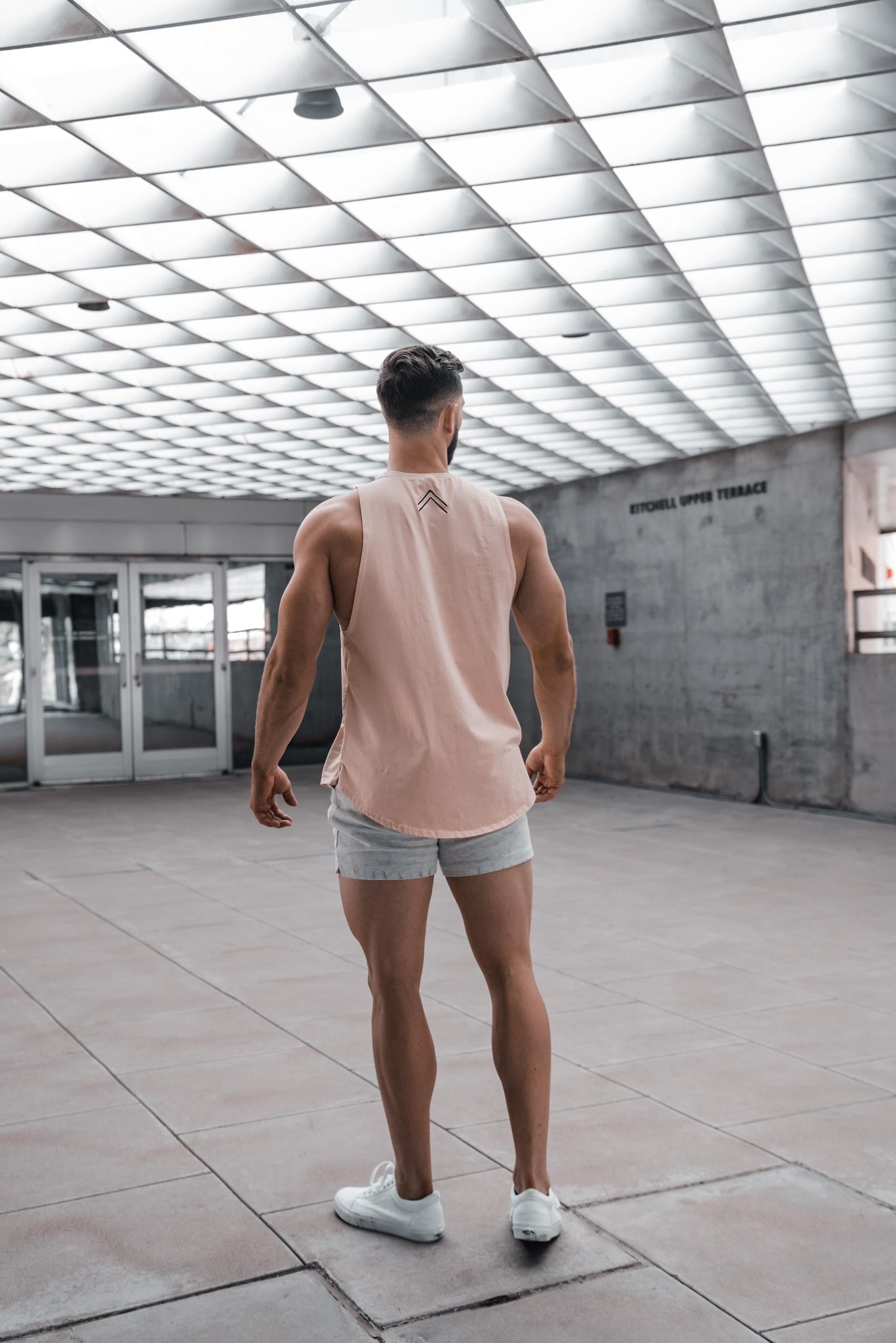 Backside view of the salmon Total Grit cut-off tank. Showing the ^^ double caret logo symbolizing "Create Your Own Reality".