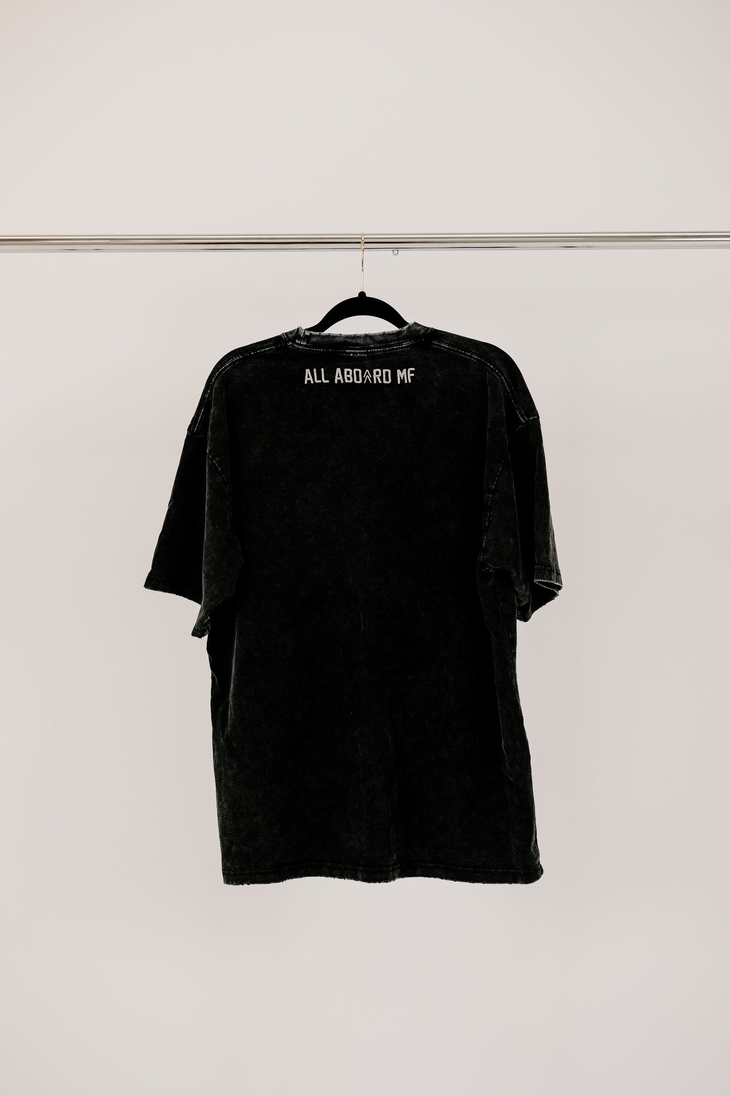 Backside view of the Gain Train tee showing off the "ALL ABOARD MF" on the black washed fabric.