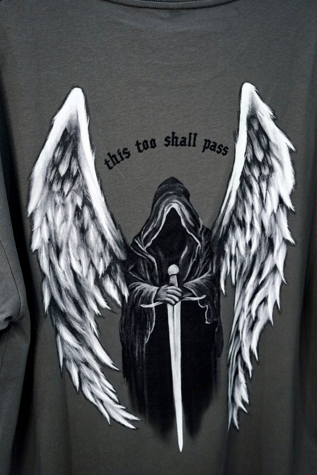 Up close & personal shot of the Angel of Death design, reading "this too shall pass"