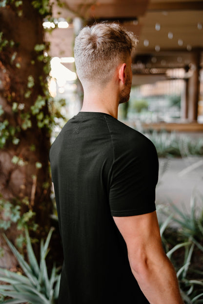 Model showing off the backside view of our double caret logo on the black on black fitted tee.