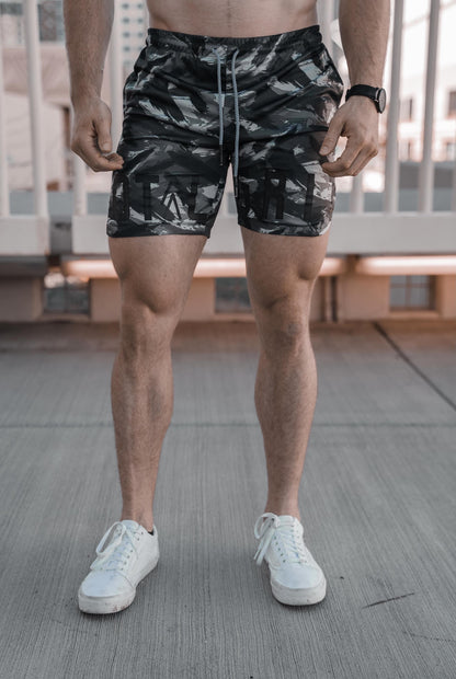 Front on shot of the dark grey camo shorts, showing an all encompassing view of the camo design, and total grit lettering across the front.